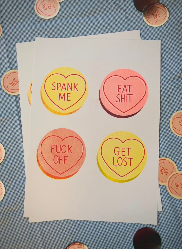 A3 risograph print of insulting love hearts candy in yellow, red and fluorescent pink.